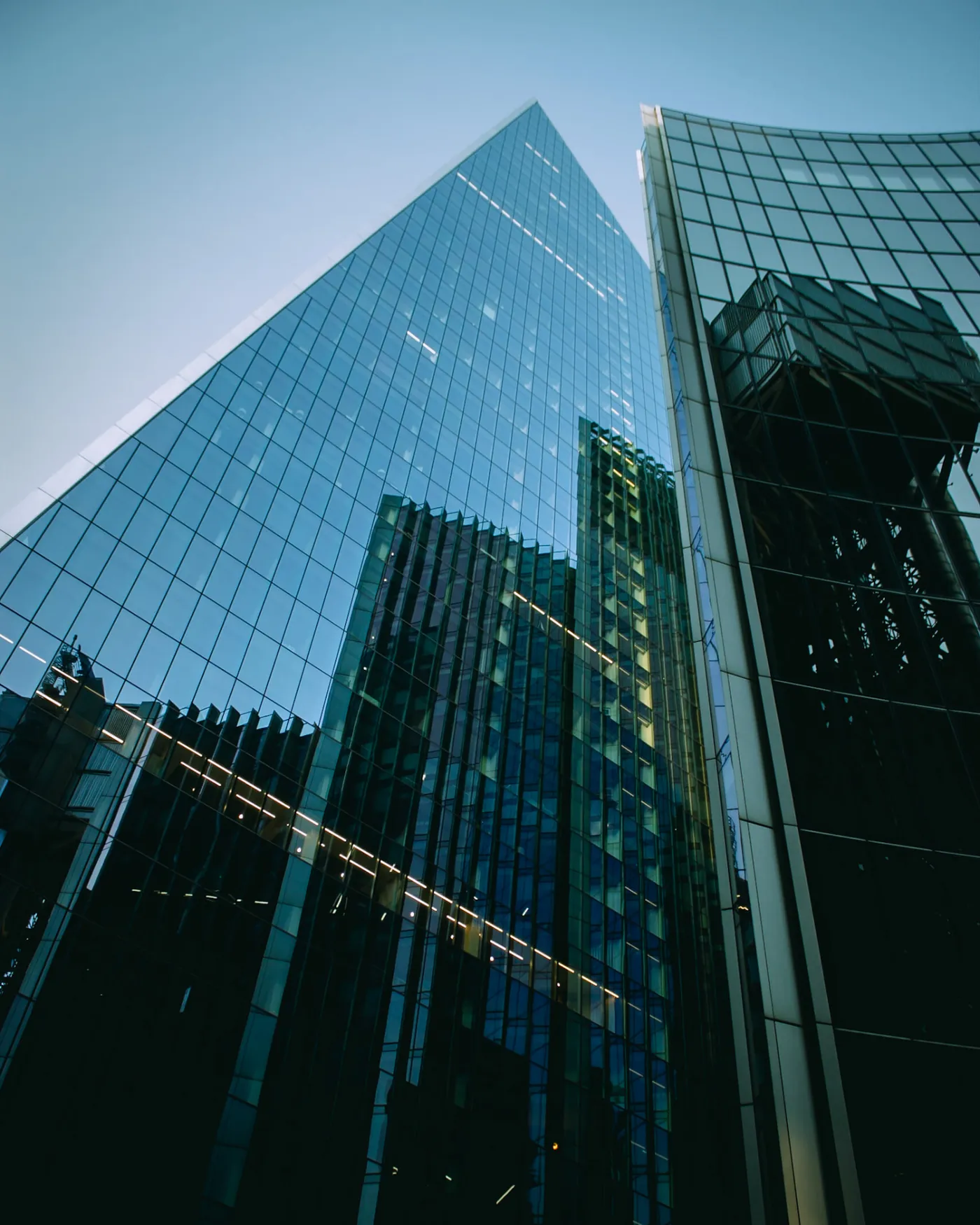 Glass skyscraper facade reflecting surrounding City of London towers